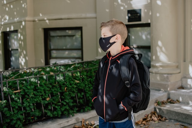 boy walking to school with black mask on